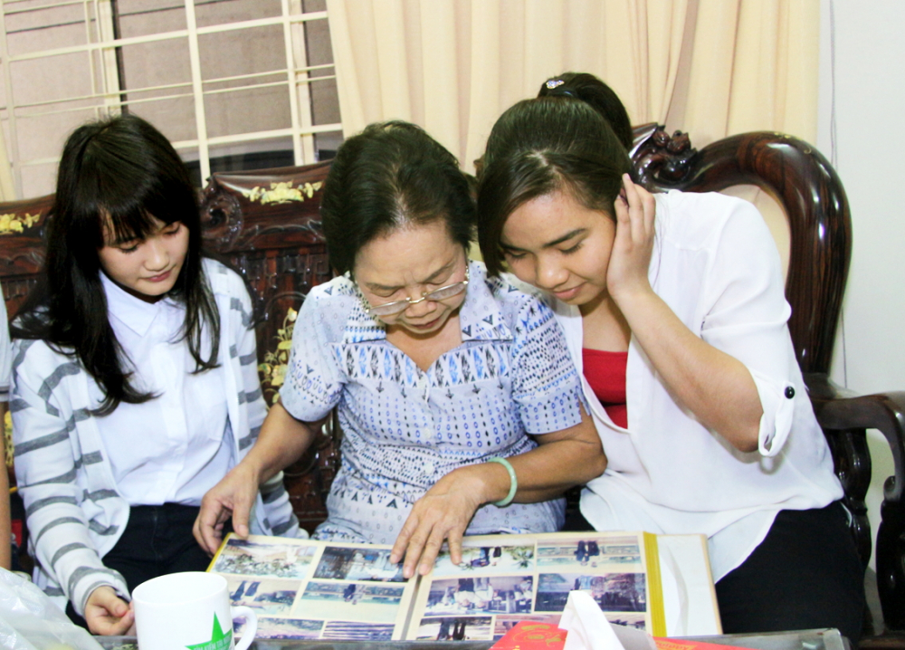 Nữ biệt động “chim sắt” Lê Thị Thu Nguyệt (giữa) lần giở những tấm ảnh kỷ vật, kể lại những ngày chiến đấu mưu trí, dũng cảm cho các bạn trẻ - Ảnh: H.L.