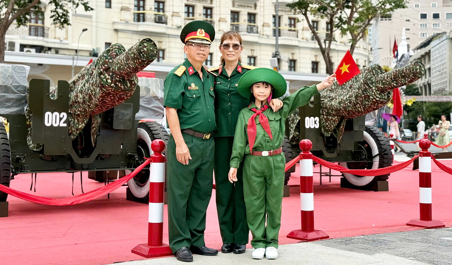Bé Nguyễn Lưu Gia An chụp hình lưu niệm với các ông bà cựu chiến binh  bên các khẩu pháo được trưng bày trang trọng ở bến Bạch Đằng - ẢNH: CHÍ THIỆN
