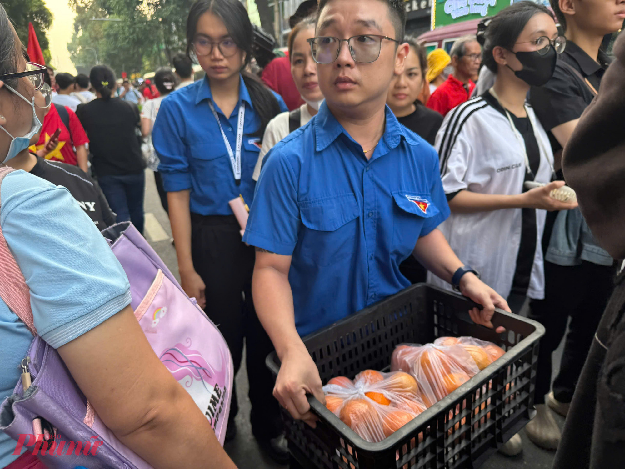 Các đoàn viên thuộc Quận đoàn Quận 5 mang từng sọt trái cây chia đều cho các xe