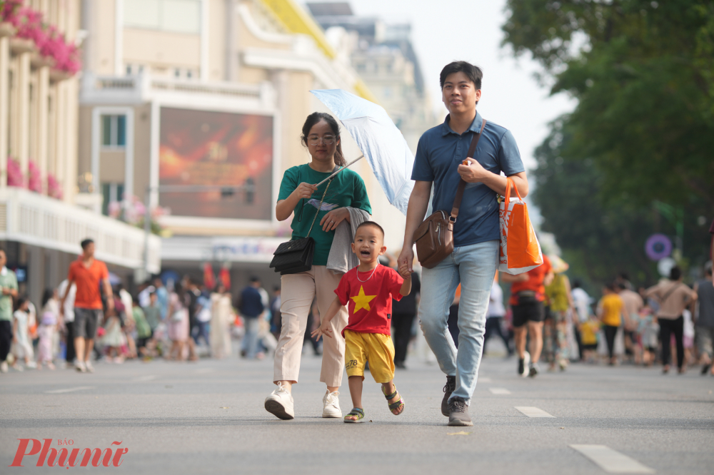 Lá cờ Tổ quốc tung bay trên tay em nhỏ, trên mũ người già và cả trên ngực áo những bạn trẻ. Một bản hòa ca rực rỡ của màu đỏ yêu nước.