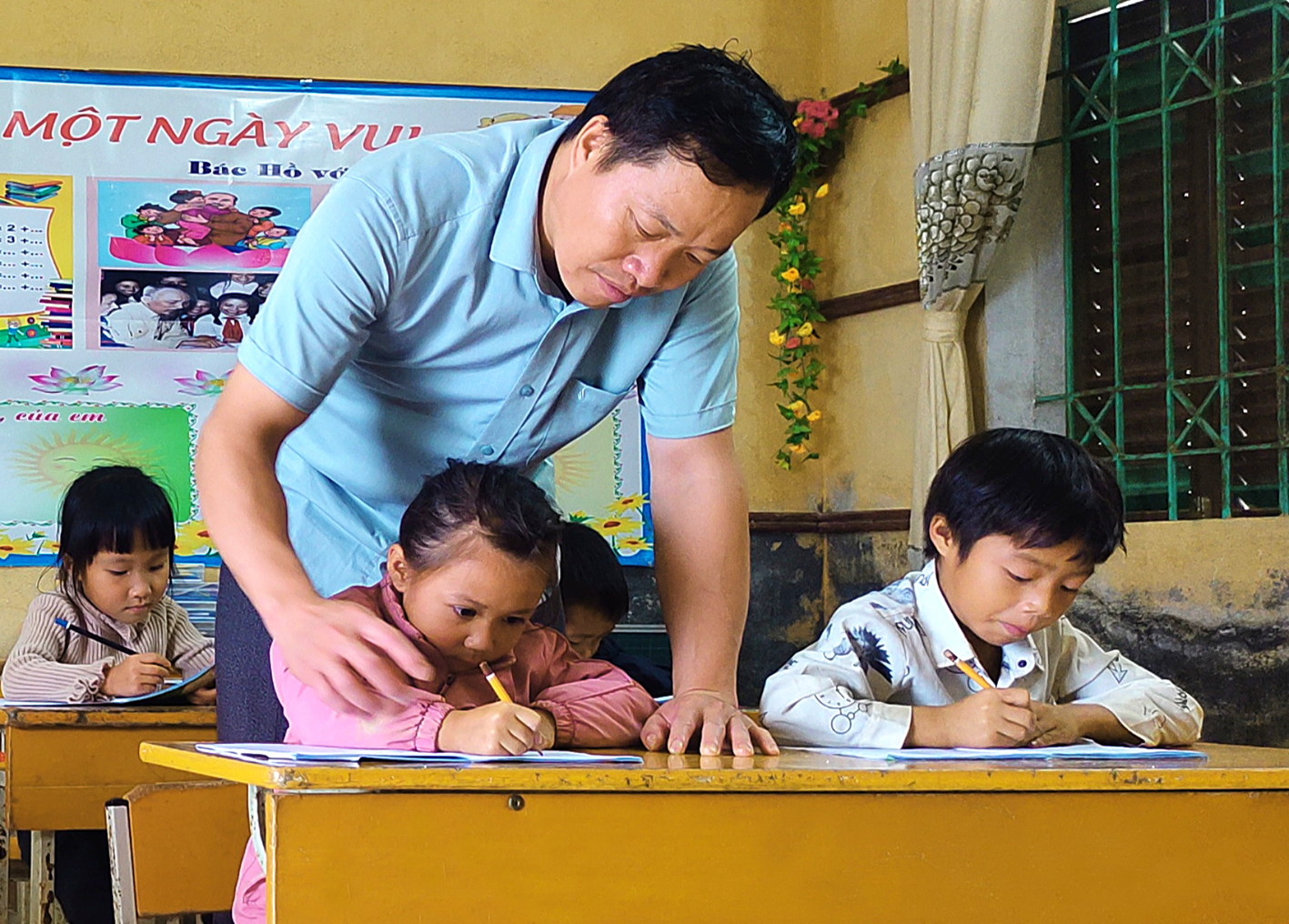 Thầy Hà Lô Tuấn hướng dẫn học sinh lớp Một viết chữ - ẢNH: L.T.