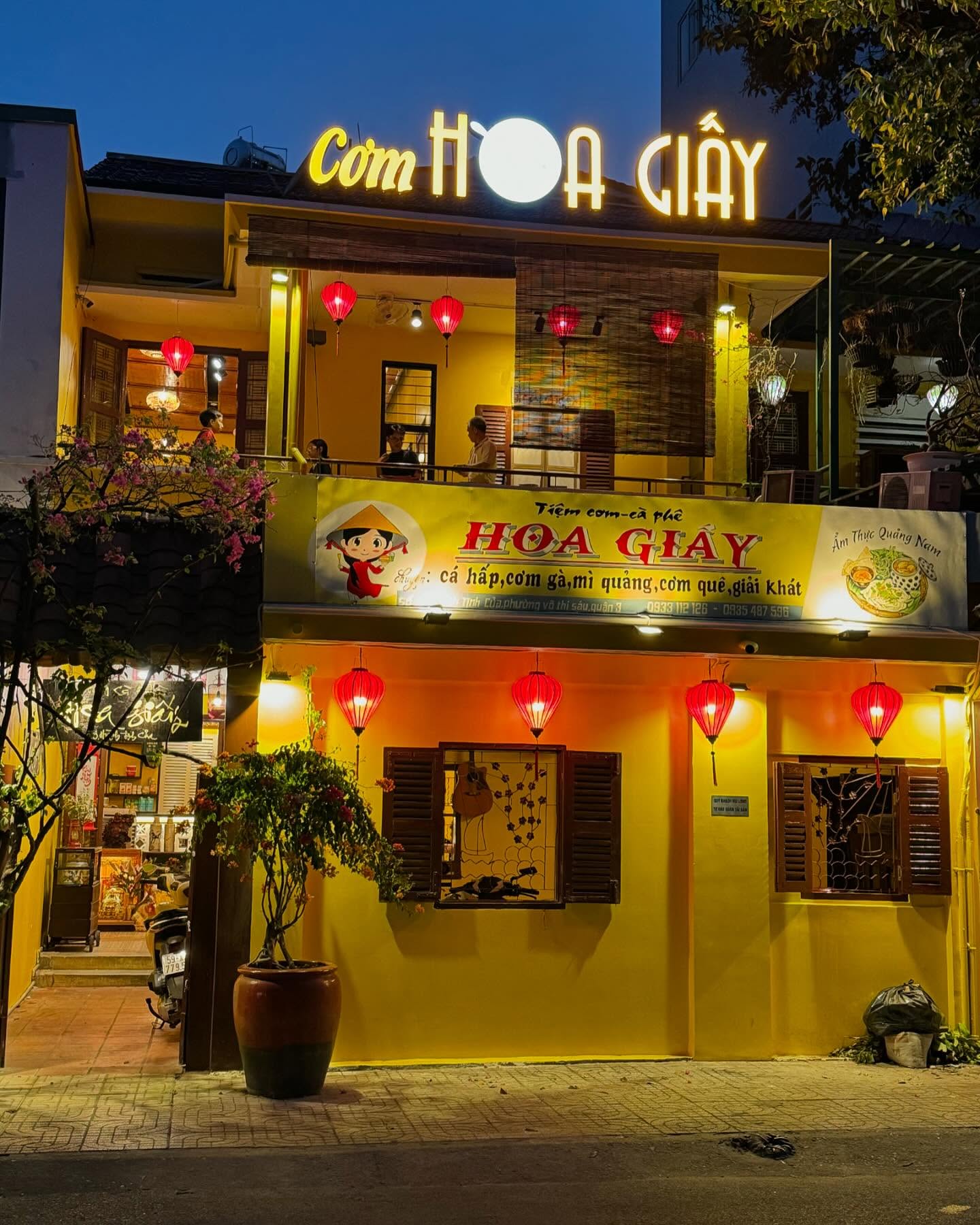 Tiệm Cơm, Cafe Hoa Giấy tọa lạc tại 19 Huỳnh Tịnh Của, phường 8, Quận 3, TP.HCM, là điểm đến quen thuộc với không gian hoài cổ, ấm cúng và nhiều góc sống ảo đẹp mắt. Quán có thiết kế vintage với tường vàng, giàn hoa giấy đặc trưng tạo cảm giác gần gũi, yên bình như ở Hội An. Không gian tầng trên rộng rãi, có cả khu vực ngoài trời thoáng mát, phù hợp tụ tập bạn bè hoặc thư giãn.