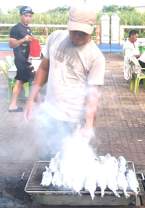 Cá ồ quấn giấy bạc nướng trên lửa than. 