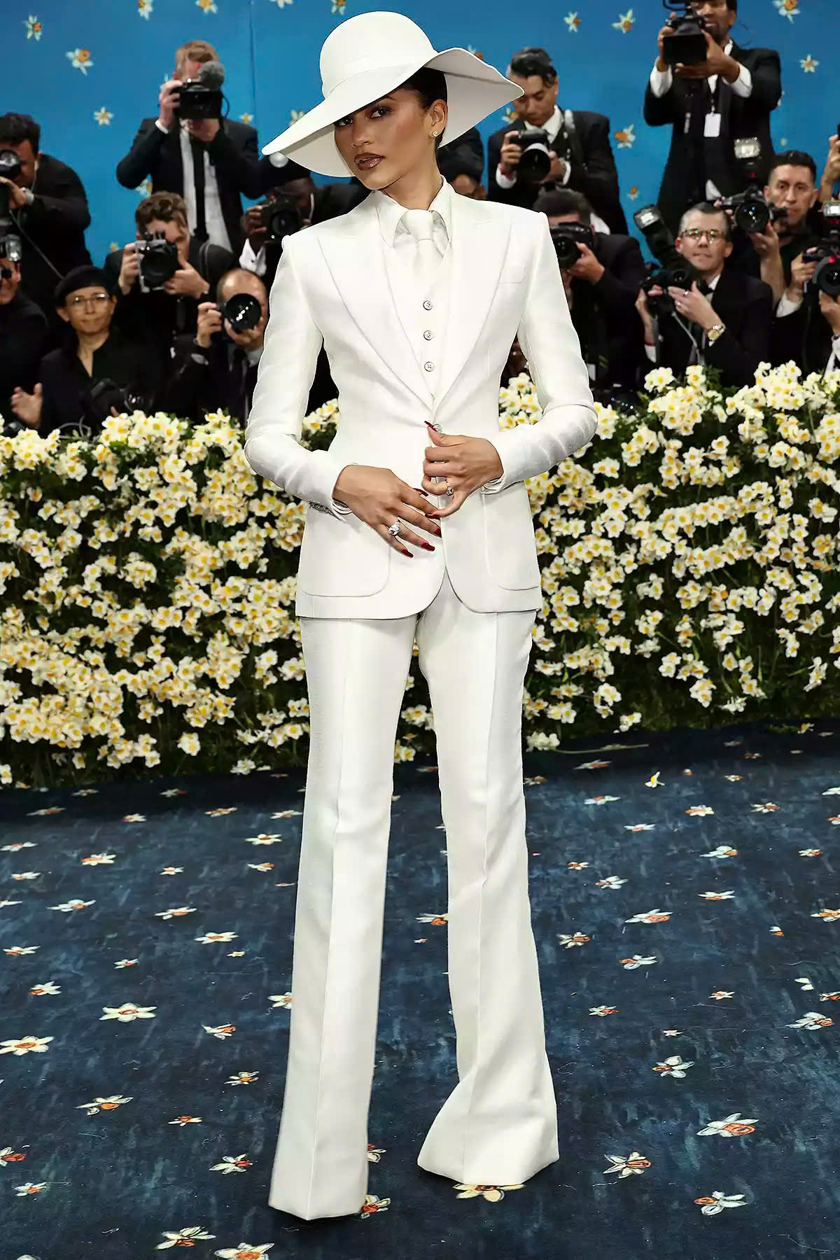 Vẫn slay như thường lệ, Zendaya đơn giản mà đúng chủ đề trong bộ suit trắng classic của Louis Vuitton cùng chiếc mũ rộng vành ton sur ton, được lấy cảm hứng từ Bianca Jagger and Diana Ross. Dù chiếc mũ che nửa gương mặt nhưng nữ diễn viên vẫn khiến dân tình khó rời mắt với thần thái ngút ngàn.