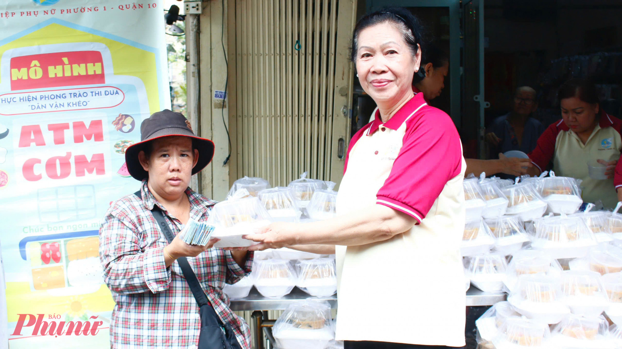 Chị Trần Thị Kim Nhung - 44 tuổi (bìa trái), làm nghề bán vé số, là một trong những hộ gia đình thường xuyên nhận cơm từ mô hình 'ATM cơm cho cả nhà.' Gia đình chị hiện chỉ còn 4 người, trong đó chỉ có 2 người có khả năng lao động với thu nhập rất ít ỏi. Nhờ vào những suất cơm yêu thương, chị giảm bớt phần nào chi phí sinh hoạt, được tiếp sức vươn lên.