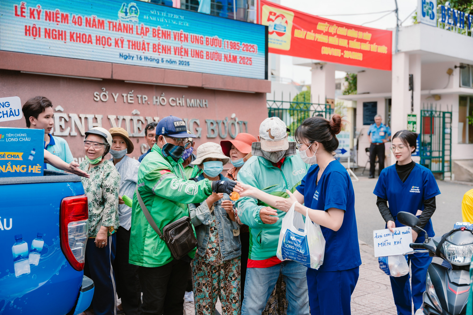 Những tài xế công nghệ, người bán hàng rong, người dân xếp hàng chờ thăm khám... ghé nhận nước uống miễn phí giữa trưa nắng gắt - Ảnh: FPT Long Châu