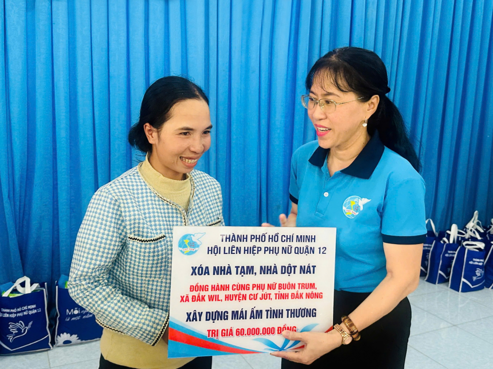 Những nhịp cầu của yêu thương và hy vọng Bà Trương Nhựt Thẫm (bìa phải) - Chủ tịch Hội LHPN quận 12 - trao bảng tượng trưng hỗ trợ kinh phí cho gia đình chị H’Yung Byã xây nhà