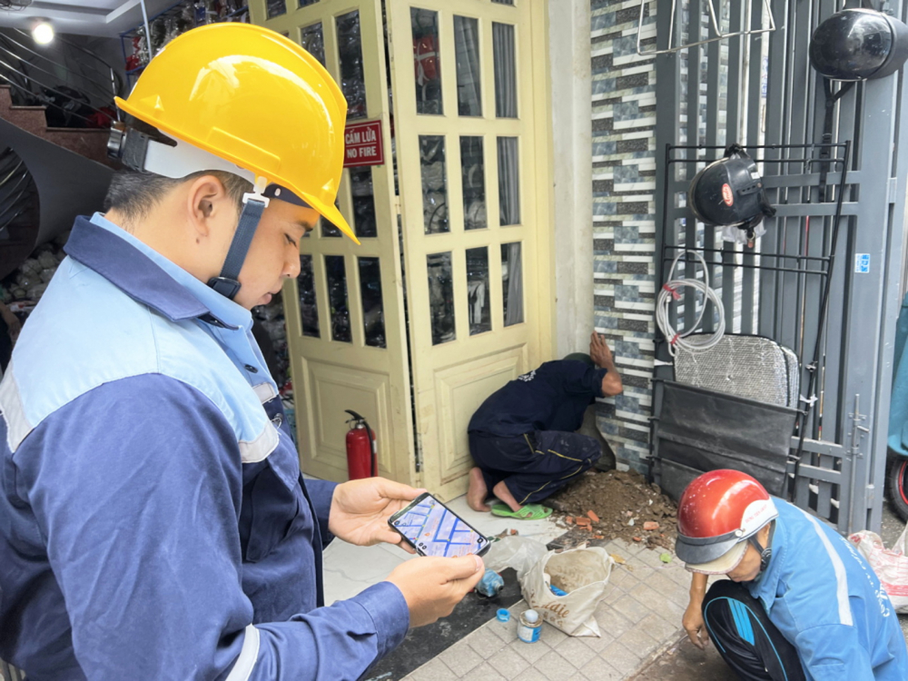 Nhân viên của Công ty cổ phần Cấp nước Trung An theo dõi hệ thống đường ống  trên ứng dụng GIS khi thay đồng hồ nước cho khách hàng - ẢNH: DIỄM MI