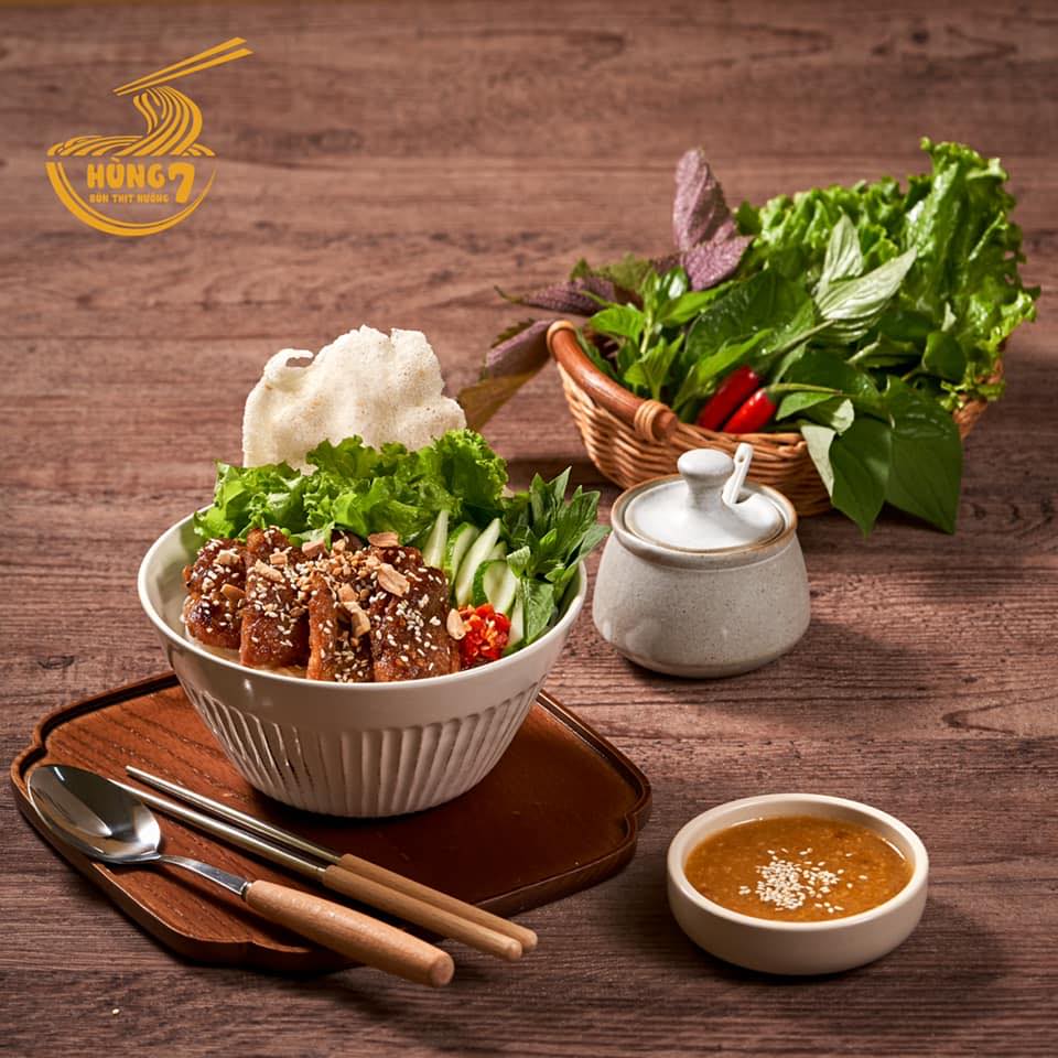 4. Bún thịt nướng, bún mắm nêm – Món khô, mát bụng Giữa ngày nóng bức, chỉ nghĩ tới việc ăn một tô bún nghi ngút khói đã thấy... đổ mồ hôi. Vậy nên, những món “bún khô” như bún thịt nướng hay bún mắm nêm luôn chiếm ưu thế. Bún nguội, rau sống giòn mát, thịt nướng thơm lừng, thêm chút đồ chua, đậu phộng và mỡ hành, chan nhẹ nước mắm pha hoặc mắm nêm đậm đà – đủ vị mà không nặng bụng. Món này còn có ưu điểm là no lâu mà không gây ngấy, lại bổ sung được rau xanh và chất đạm cần thiết. Một số quán được dân sành ăn yêu thích là Hải Đăng (Nguyễn Văn Đậu), bún mắm nêm Cô Ba (Trường Sa), hay các tiệm bún Đà Nẵng ở Vạn Kiếp. Giá mỗi tô dao động từ 35.000 – 55.000 đồng. Không ồn ào, không bốc khói, chỉ nhẹ nhàng thơm mát như một buổi trưa râm mát giữa lòng phố thị.