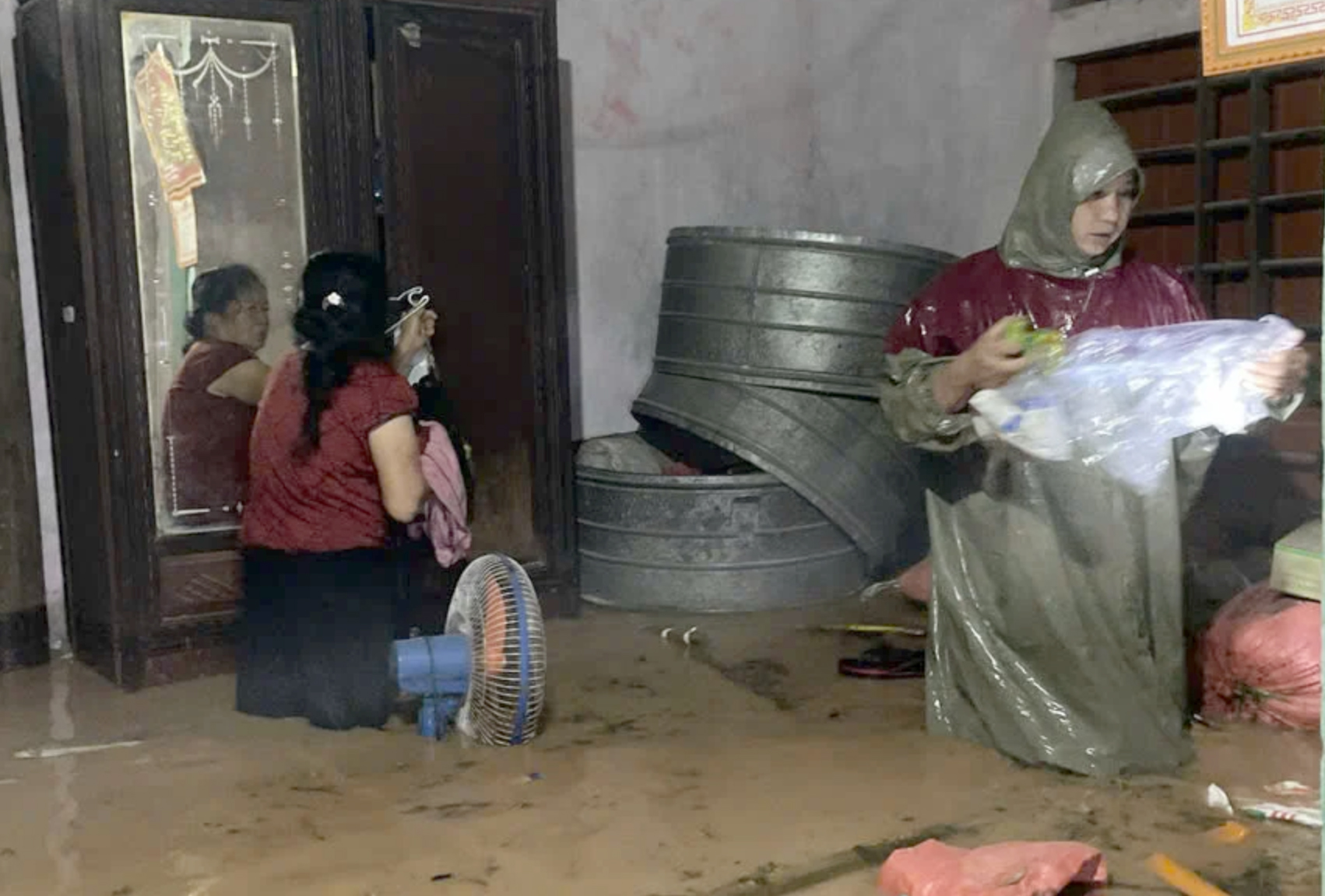 Người dân tất tả kê cao tài sản khi nước tràn vào nhà giữa đêm khuya - Ảnh: Phạm Quân