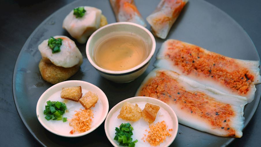 Bánh nậm là món bánh truyền thống nổi tiếng xứ Huế, có hình dáng mỏng, dẹt và được gói trong lá chuối. Vỏ bánh mềm mịn làm từ bột gạo pha bột năng, phần nhân là tôm thịt xào đậm đà cùng hành phi và dầu điều. Bánh được hấp chín, khi bóc lớp lá chuối, hương thơm dân dã lan tỏa quyến rũ. Thực khách thường ăn kèm nước mắm pha chua ngọt, tạo nên sự hài hòa vị giác. Nhờ dễ gói, dễ mang đi, bánh nậm phổ biến tại các chợ Huế và là món ăn nhẹ được người dân lẫn du khách yêu thích.