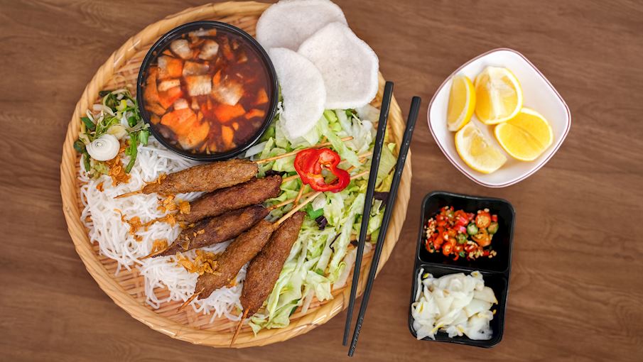 Nem lụi Huế là món nướng dân dã nhưng đầy hấp dẫn, được làm từ thịt heo xay trộn với tiêu, tỏi, hành, nước mắm và đôi khi có cả da heo. Thịt được vo quanh que sả rồi nướng trên than hồng đến khi dậy mùi thơm và hơi xém cạnh. Khi ăn, nem lụi được cuốn cùng bánh tráng, rau sống, dưa leo, khế chua và chấm nước sốt đặc biệt làm từ đậu phộng và mè. Vị béo, thơm và cay nhẹ của món ăn này tạo nên trải nghiệm đậm chất Huế, rất phù hợp cho bữa xế hoặc món chính nhẹ nhàng.