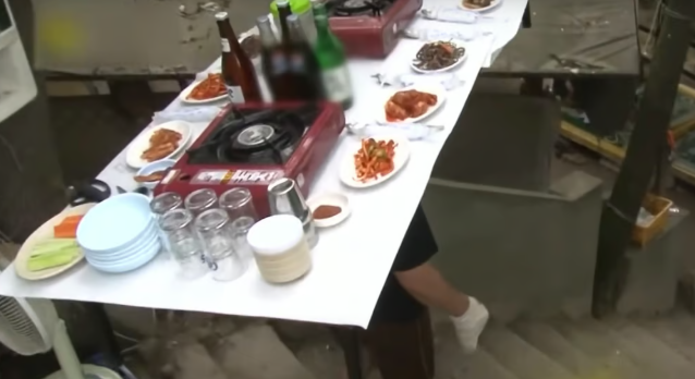 Kang Jin-gyu với một chiếc bàn đầy chất trên đầu. Anh ấy chuyển sang thực hiện các đơn đặt hàng thực phẩm theo cách này sau khi bàn tay của anh ấy bị đau khi phục vụ theo truyền thống. Ảnh: YouTube
