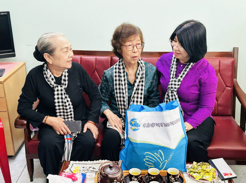 Bà Hoàng Thị Khánh (bìa trái) - Trưởng ban Liên lạc Cựu tù chính trị và tù binh TPHCM - và bà Trần Thị Huyền Thanh (bìa phải) - Phó chủ tịch Hội LHPN TPHCM - thăm hỏi bà Lưu Kim Hoa - thành viên trong một gia đình nòng cốt của phong trào công nhân tại hãng dệt Vimytex