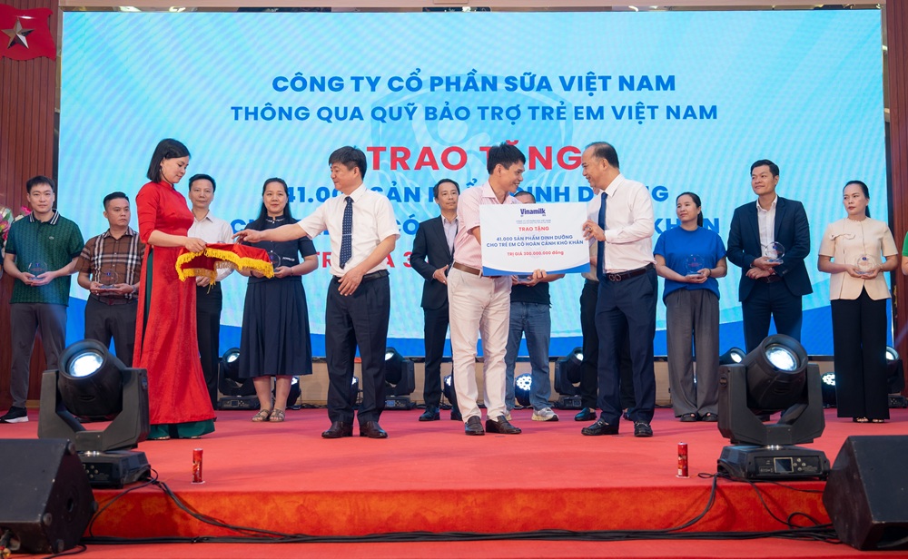 Ông Phạm Tuyên - Giám đốc chi nhánh Vinamilk Hà Nội (đứng giữa) trao bảng tượng trưng món quà 41.000 hộp sữa cho trẻ em Phú Thọ - Ảnh: Minh Hà