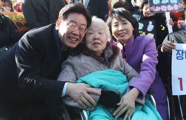 Ông Lee Jae-myung (bên trái) khi đó là thị trưởng Seongnam, chụp ảnh cùng mẹ Koo Ho-myung (ở giữa), và vợ Kim Hye-kyung, tại một nhà máy đồng hồ ở Seongnam, tỉnh Gyeonggi, nơi ông làm việc khi còn là công nhân - Ảnh: Yonhap