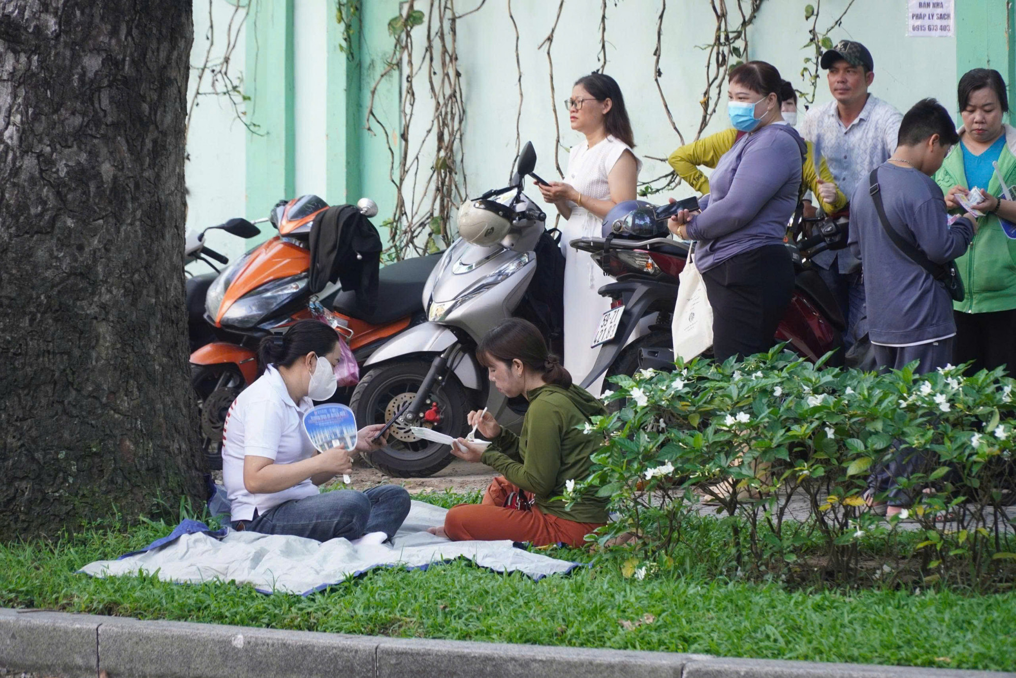 Phụ huynh tại điểm thi Trường THPT Trưng Vương (quận 1) tranh thủ ăn sáng trong lúc đợi con thi - Ảnh: Trang Thư
