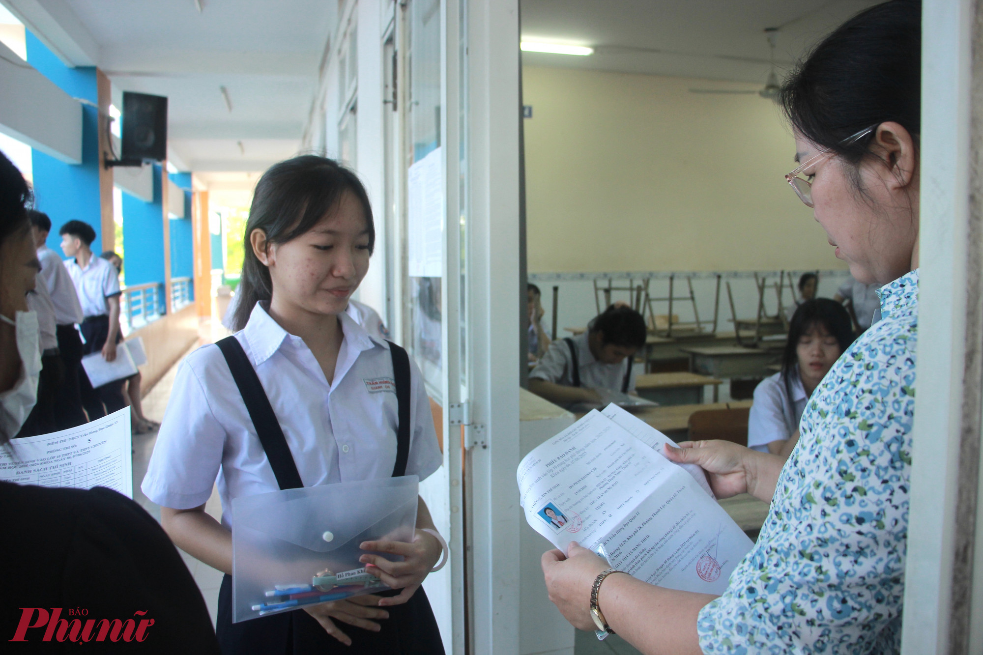 7g thí sinh lần lượt được giám thị đọc tên, kiểm tra giấy tờ, vật dụng mang theo trước khi bước vào phòng thi 