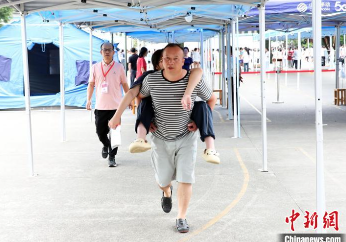 Cao Quang Hưng bế con gái Cao Yalin vào địa điểm thi vào ngày 7 tháng 6 năm 2025, ngày đầu tiên của Gaokao, tại huyện tự trị Tamjiang Đông, khu tự trị Quảng Tây Zhuang. [Ảnh/Chinanews.com]