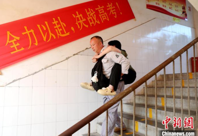 Cao Quang Hưng bế con gái Cao Yalin vào địa điểm thi vào ngày 7 tháng 6 năm 2025, ngày đầu tiên của Gaokao, tại huyện tự trị Tamjiang Đông, khu tự trị Quảng Tây Zhuang. [Ảnh/Chinanews.com]