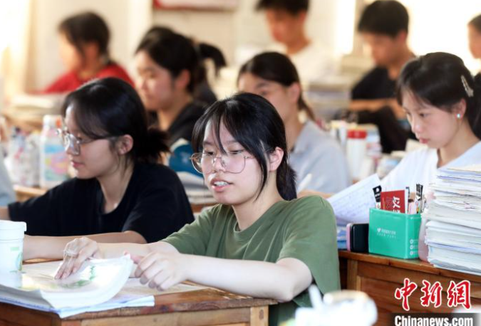 Cao Quang Hưng bế con gái Cao Yalin vào địa điểm thi vào ngày 7 tháng 6 năm 2025, ngày đầu tiên của Gaokao, tại huyện tự trị Tamjiang Đông, khu tự trị Quảng Tây Zhuang. [Ảnh/Chinanews.com]