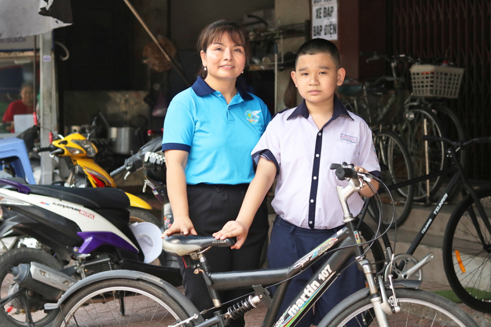 Chị Nguyễn Thị Hồng Thu mua xe đạp mới cho cháu Trần Minh Phúc - ẢNH: MẪN NHI