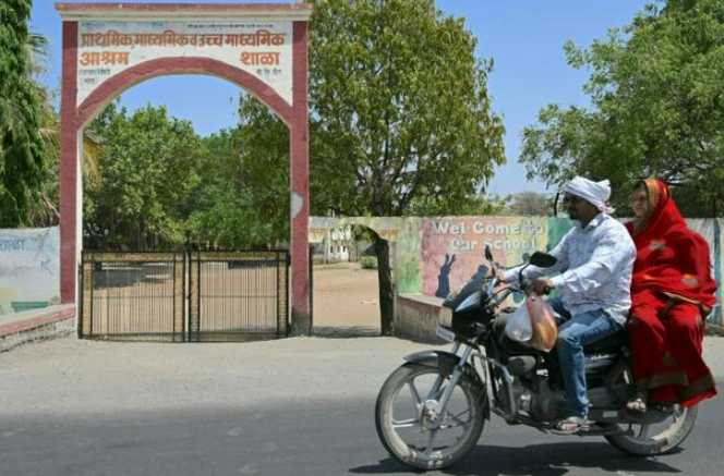 Một cặp đôi đi ngang qua một nhà trọ dành cho con em công nhân mía đường ở làng Umrad Khalsa, Maharashtra. Ấn Độ chiếm một phần ba số cô dâu trẻ em trên thế giới, theo cơ quan trẻ em của Liên hợp quốc © Indranil MUKHERJEE / AFP