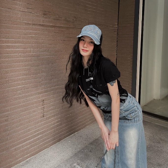 Khi đi dạo phố, em xinh Saabirose chọn áo thun đen in hình kết hợp cùng chân váy denim dài, tạo cảm giác tinh nghịch và năng động. Chi tiết loang màu trên nền vải giúp trang phục trông mềm hơn và bớt đơn điệu. Cô đội mũ lưỡi trai denim sáng màu có thêu chữ để thêm phần trẻ trung. Không thể quên thêm thắt chút gai góc qua vòng cổ dạng dây xích để tăng sự nổi bật mà không làm rối mắt.
