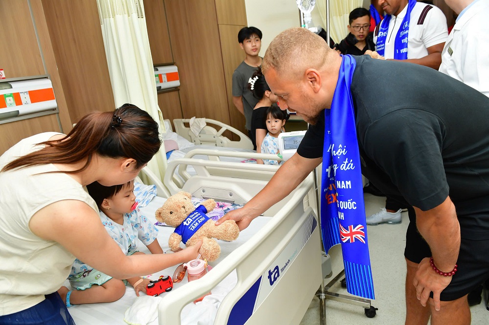 Cựu hậu vệ Wes Brown tặng quà cho một bệnh nhi nhỏ tuổi - Ảnh: Thanh Tùng/VnExpress