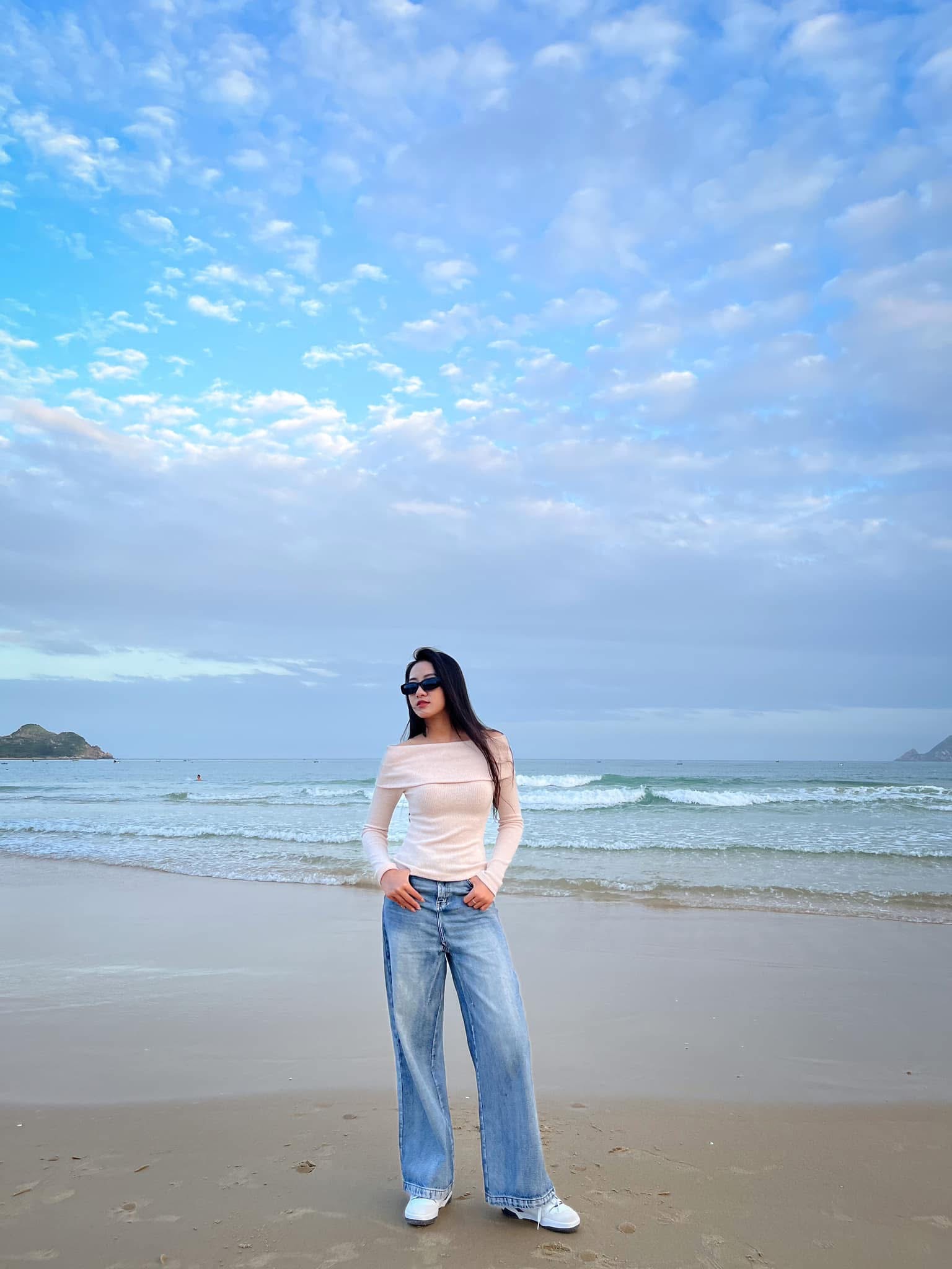 Trúc Linh phối áo trễ vai dài tay màu hồng phấn với quần jeans ống rộng cạp cao mang đến hình ảnh vừa nữ tính vừa cá tính. Set đồ giúp tôn vóc dáng và đôi chân dài của cô nàng. Giày sneaker trắng tăng thêm sự năng động, đồng thời giữ được nét khỏe khoắn, trẻ trung cho tổng thể trang phục.