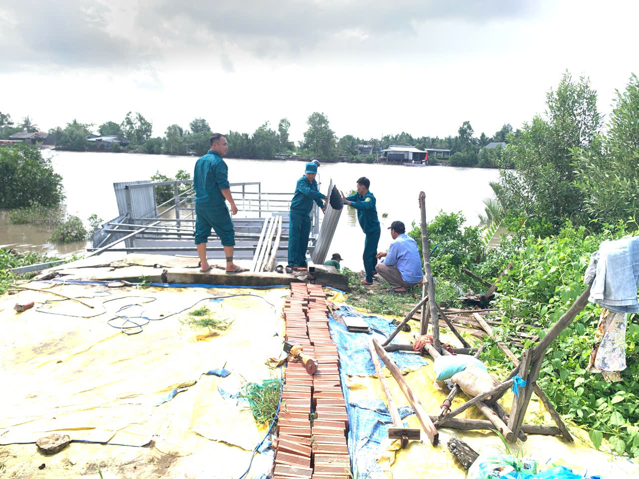 Ngành chức năng địa phương hỗ trợ người dân di dời tài sản sau khi nhà bị sụp xuống sông do sạt lở đất. Ảnh: Hoàng Thịnh