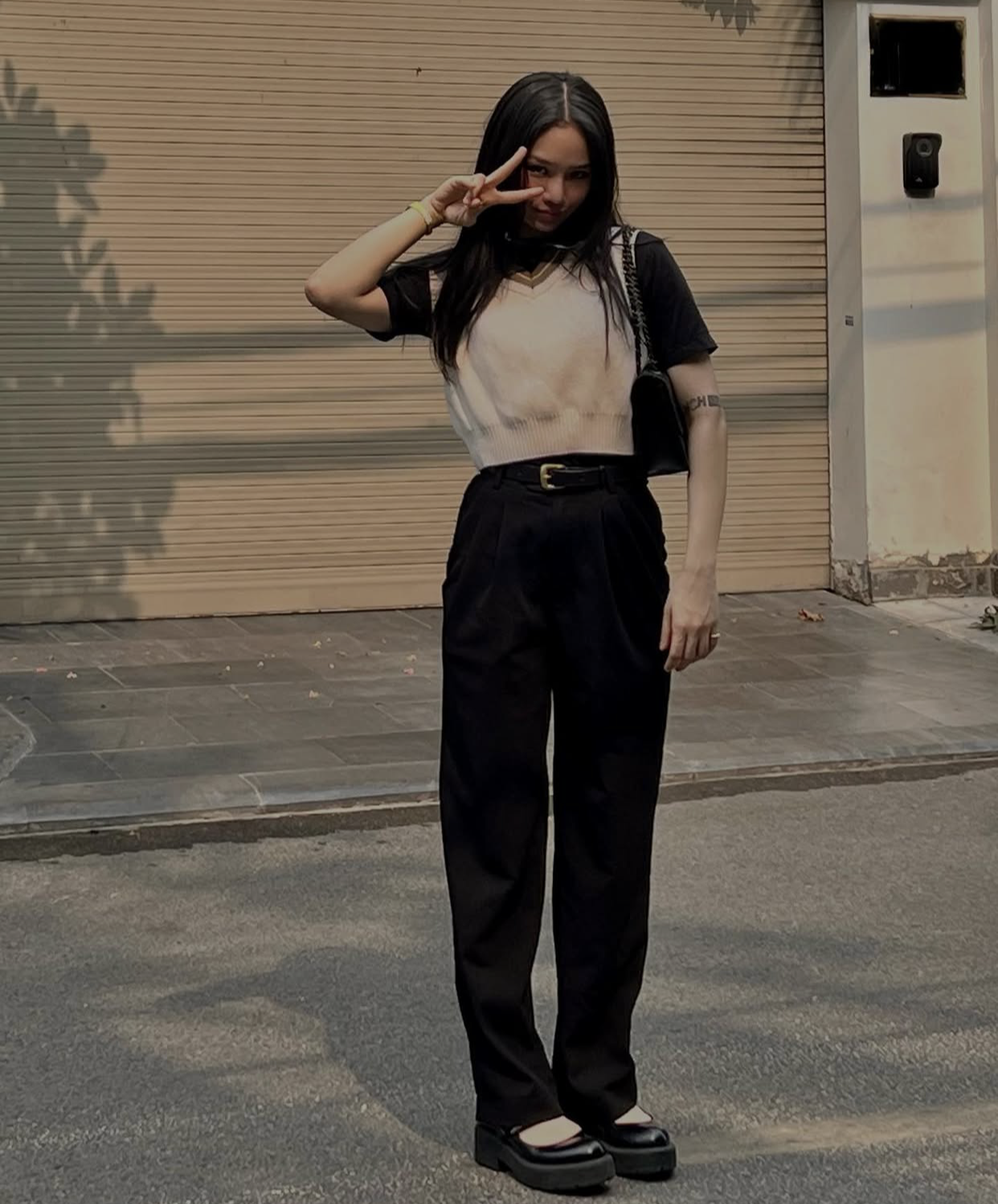 Nữ ca sĩ ghi điểm với phong cách preppy hiện đại với combo áo thun đen mix cùng áo len gile trắng, quần ống suông lưng cao và giày Mary Jane. Tổng thể đơn giản nhưng chỉn chu, toát lên vẻ trẻ trung và tinh nghịch.