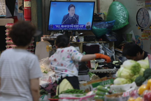 Các thương gia tại chợ Inwang ở Seodaemun-gu xem một chương trình phát sóng trực tiếp vào ngày 3 tháng 7 khi Tổng thống Lee Jae Myung tổ chức một cuộc họp báo đánh dấu 30 ngày đầu tiên của ông tại nhiệm. (Yonhap)