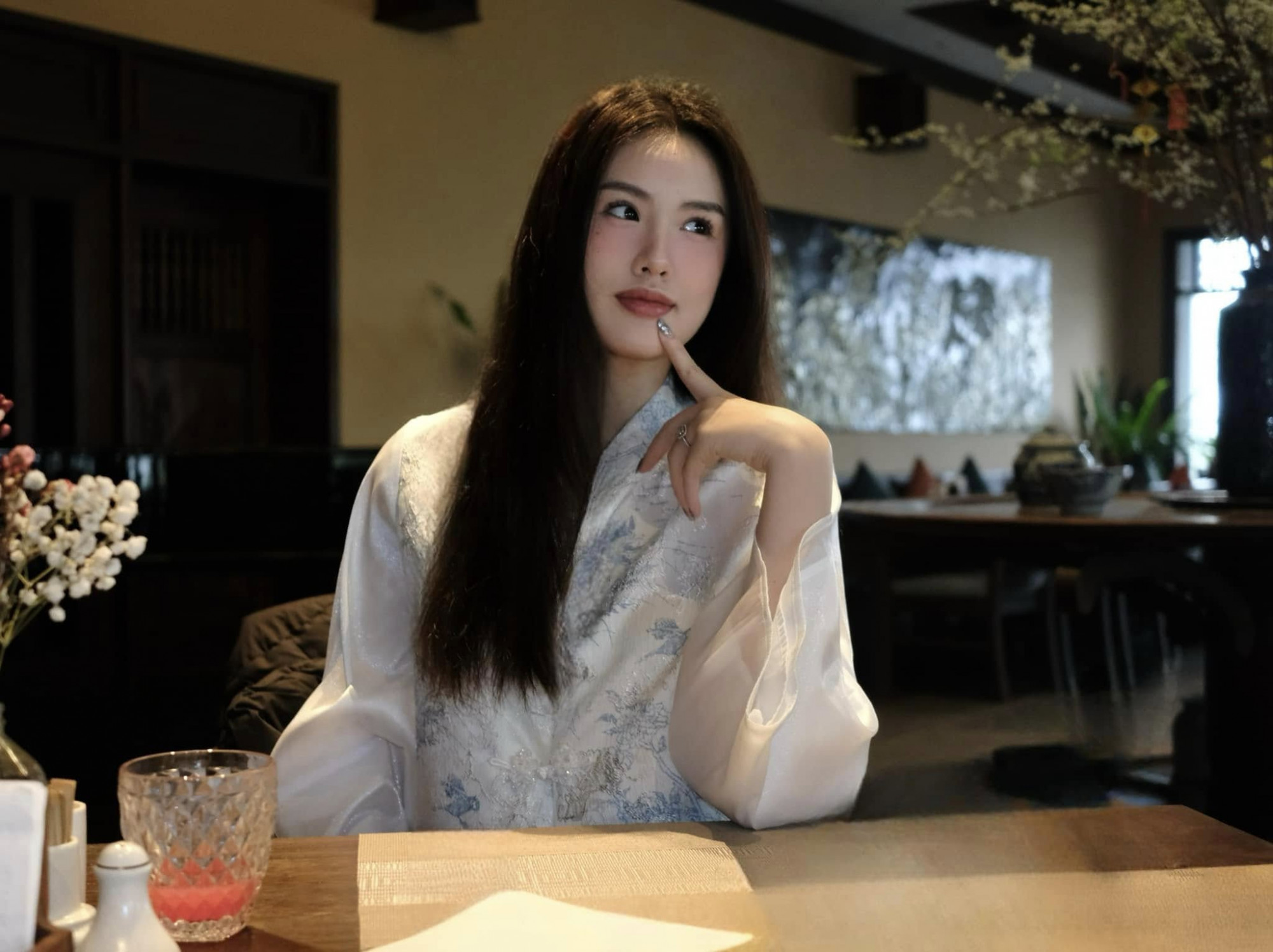 Á hậu Trịnh Mỹ Anh gây ấn tượng với vẻ đẹp Á Đông dịu dàng trong trang phục truyền thống cách tân màu trắng, thêu họa tiết tinh tế. Mái tóc xõa tự nhiên và biểu cảm nhẹ nhàng tôn lên nét thanh lịch, duyên dáng.