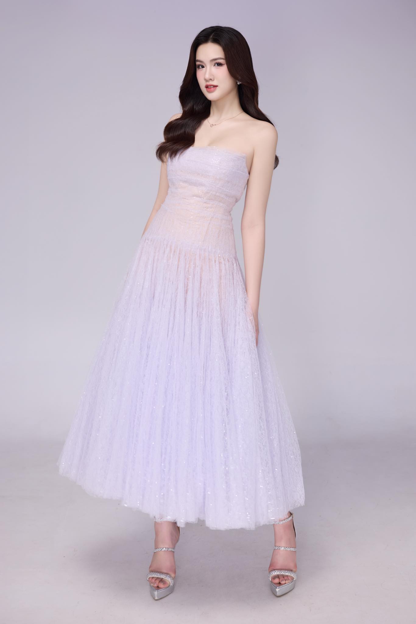 Á hậu Trịnh Mỹ Anh ghi điểm với vẻ đẹp thanh thoát trong chiếc đầm pastel ánh tím nhạt. Thiết kế cúp ngực, chất liệu voan lấp lánh cùng phần váy xòe nhẹ giúp tôn dáng và tăng nét nữ tính, sang trọng.