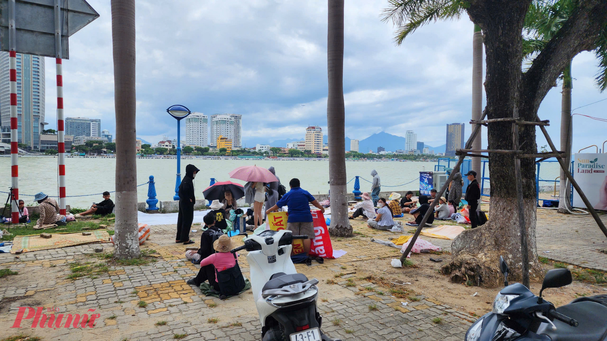 Trưa 12/7, trên vỉa hè đường Trần Hưng Đạo, phường An Hải, TP Đà Nẵng ghi nhận rất đông người dân tranh nhau trải áo mưa, bạt 