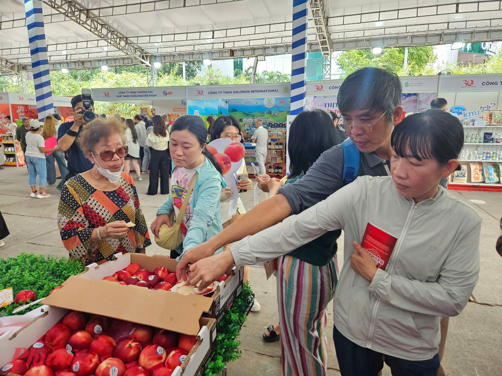 Táo Mỹ – một trong những loại trái cây nhập khẩu được người Việt ưa chuộng – được trưng bày trong thùng lớn, có tem truy xuất nguồn gốc rõ ràng. Nhiều khách tham quan dừng lại thử vị và đánh giá chất lượng sản phẩm.