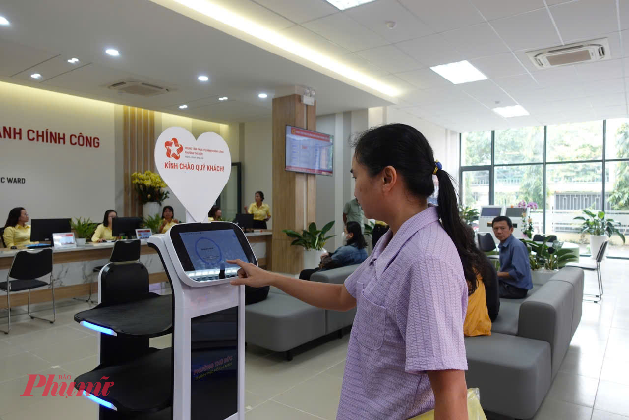 người dân đến Trung tâm phục vụ hành chính công phường Thủ Đức thực hiện thủ tục và cảm thấy thú vị với 2 robot phục vụ. 