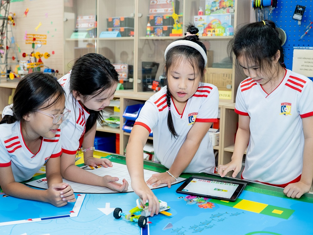 Trần Bùi Ngọc Trâm Anh (thứ hai từ phải sang) cùng bạn bè trải nghiệm điều khiển robot bằng ứng dụng thông minh - Ảnh: Royal School