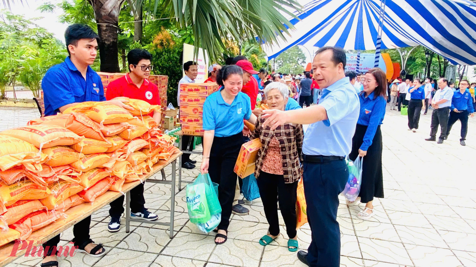 Ông Nguyễn Văn Đông - Bí thư Đảng ủy, Chủ tịch Hội đồng nhân dân phường Bình Dương, TPHCM (bìa phải) - hỗ trợ người dân nhận quà từ Phiên chợ nhân ái