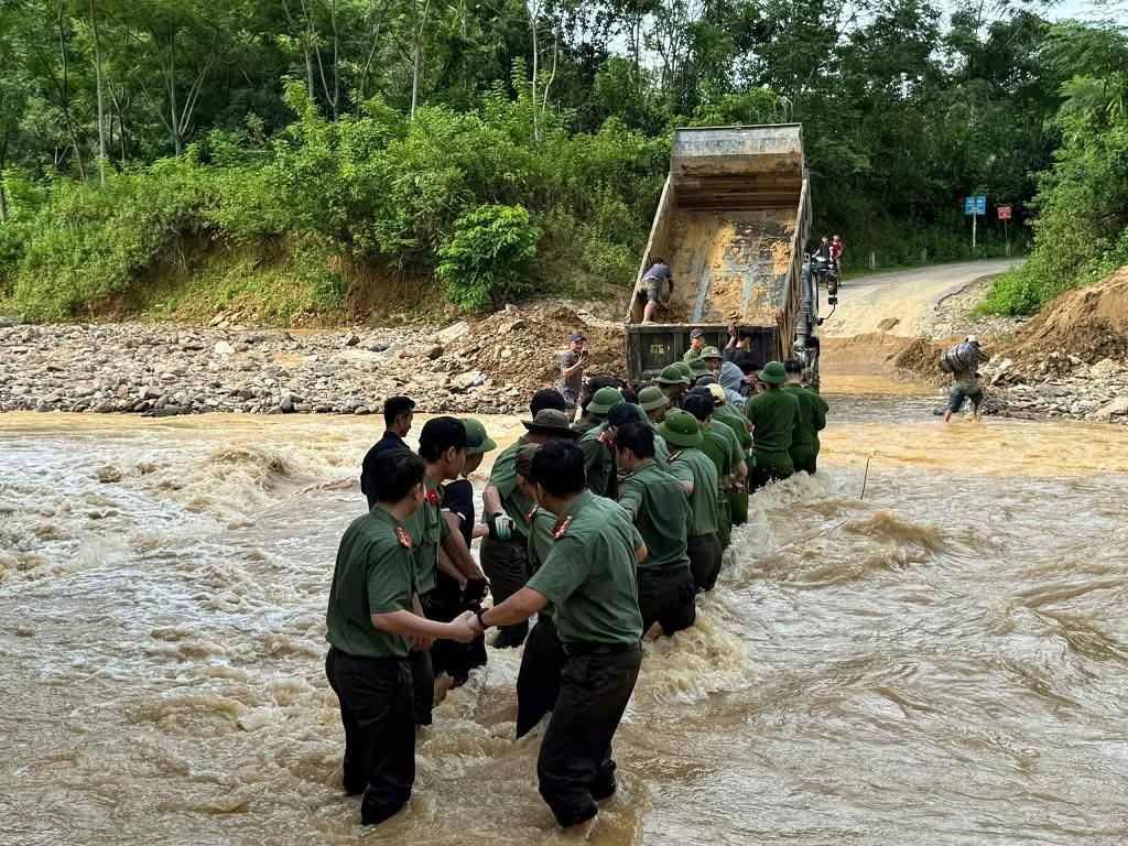 Gần 40 công an nắm tay nhau lập hàng rào sống để đưa sản phụ vượt qua dòng nước chảy xiết - Ảnh: Khánh Trung