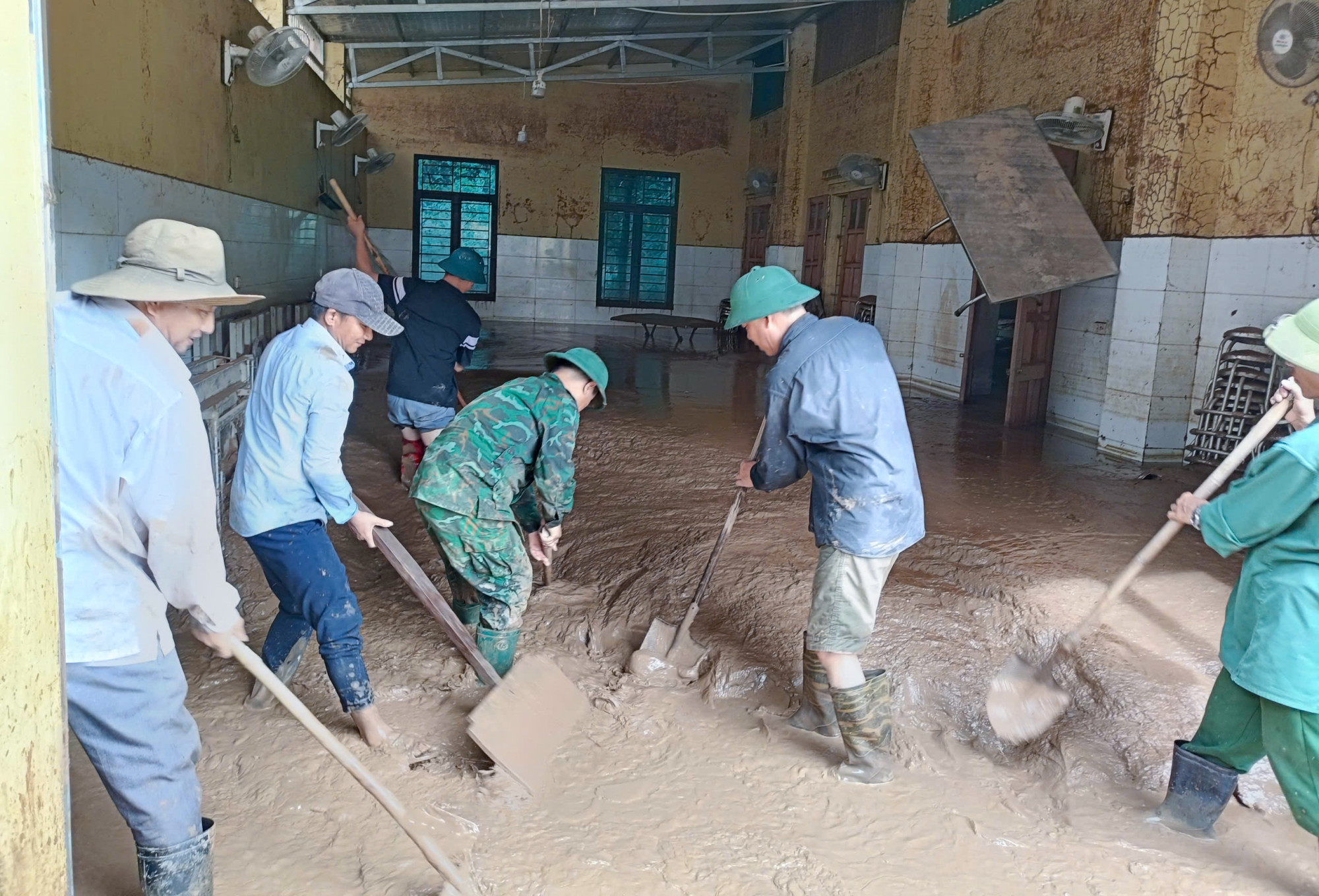 Giáo viên Trường Phổ thông DTBT tiểu học Mường Típ 2 tập dung dọn bùn đất, tìm kiếm các tài sản còn sử dụng được đưa đi sửa chữa - Ảnh: Phan Ngọc