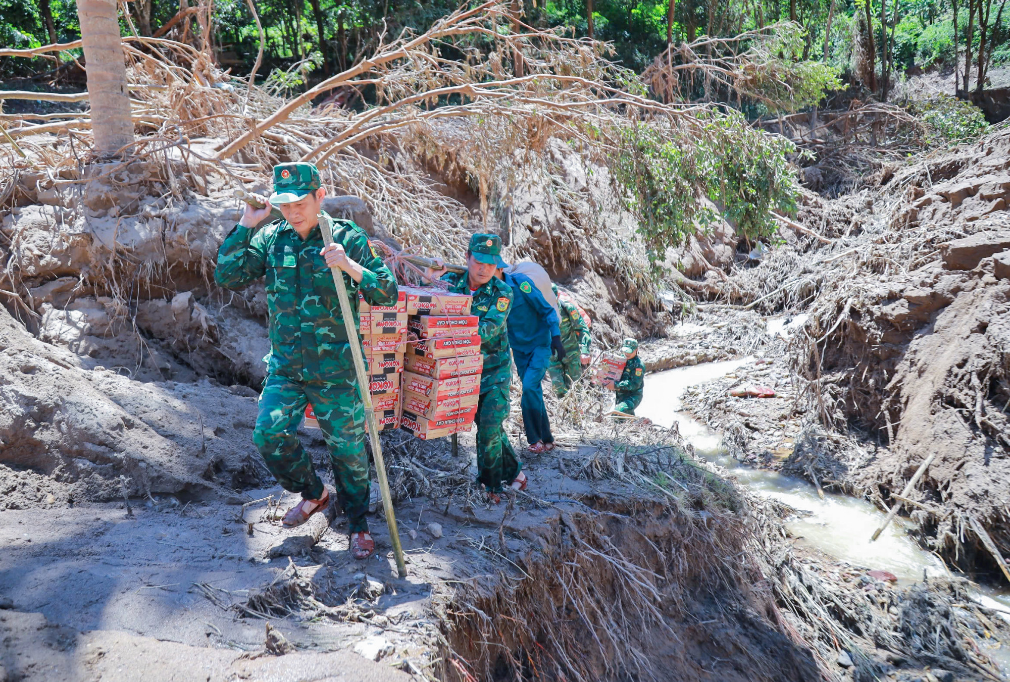 Lực lượng biên phòng gánh nhu yếu phẩm vào tiếp tế cho người dân ở các bản vùng biên bị cô lập sau lũ - Ảnh: Khánh Trung