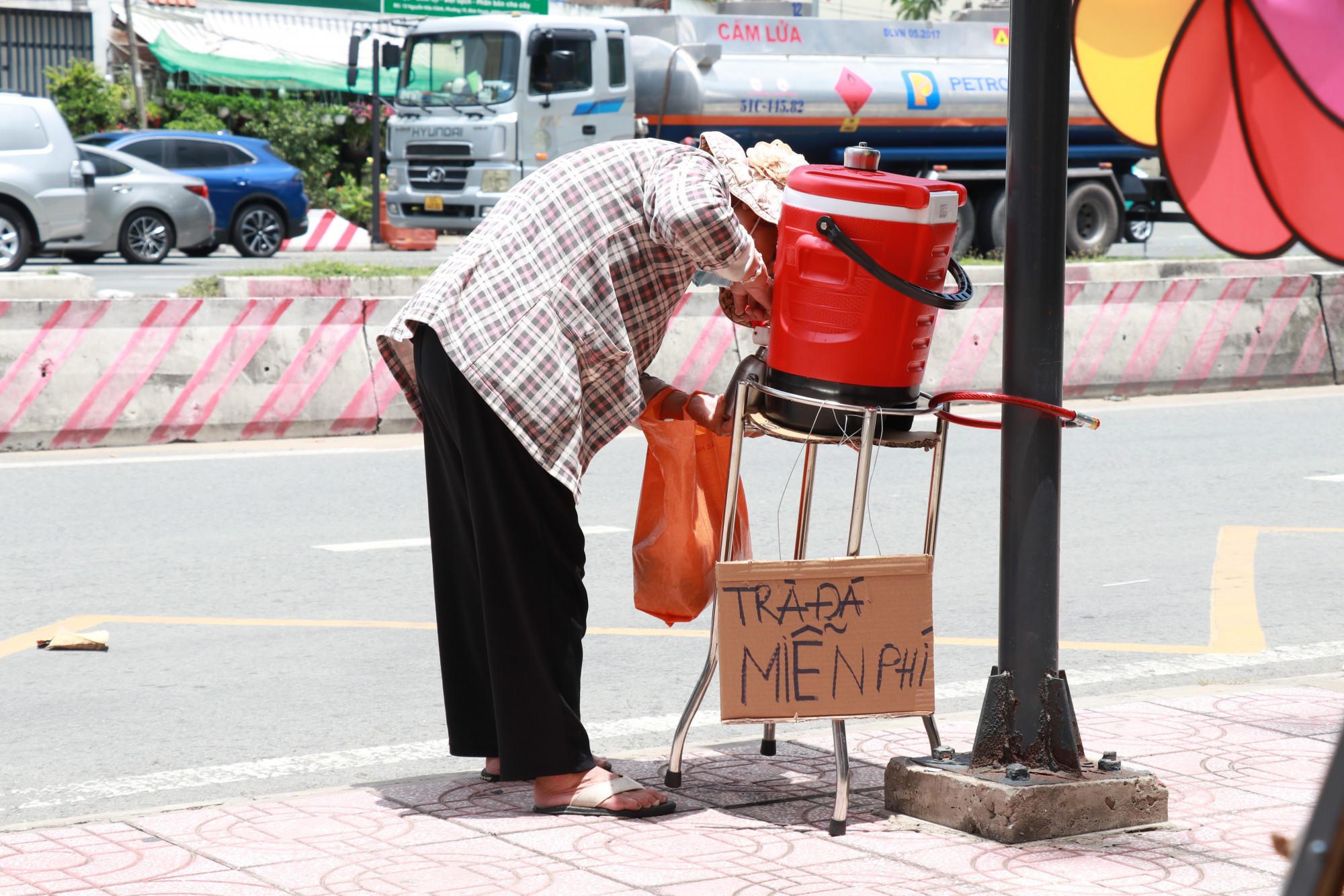 Người dân đến lấy trà đá miễn phí được quán đặt tại trạm xe bus trên vỉa hè