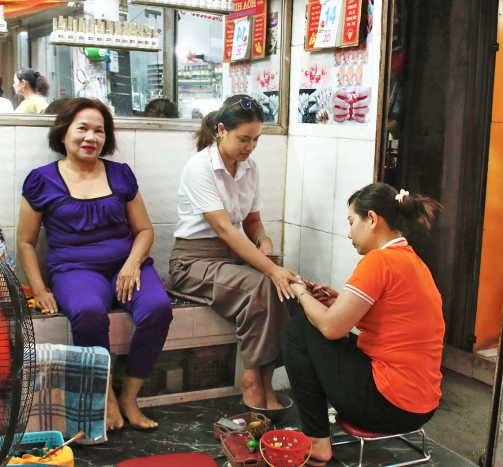 Chị Phạm Thị Bích Đào kiếm thêm thu nhập từ nghề làm móng tại chợ Nhật Tảo  - ẢNH: NGỌC TRĂM