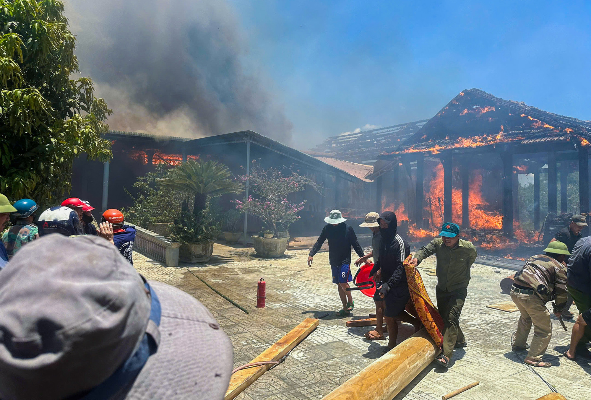 Người dân hô hoán nhau giúp gia chủ di dời một số khúc gỗ ra ngoài, vớt vát tài sản - Ảnh: Khánh Trung