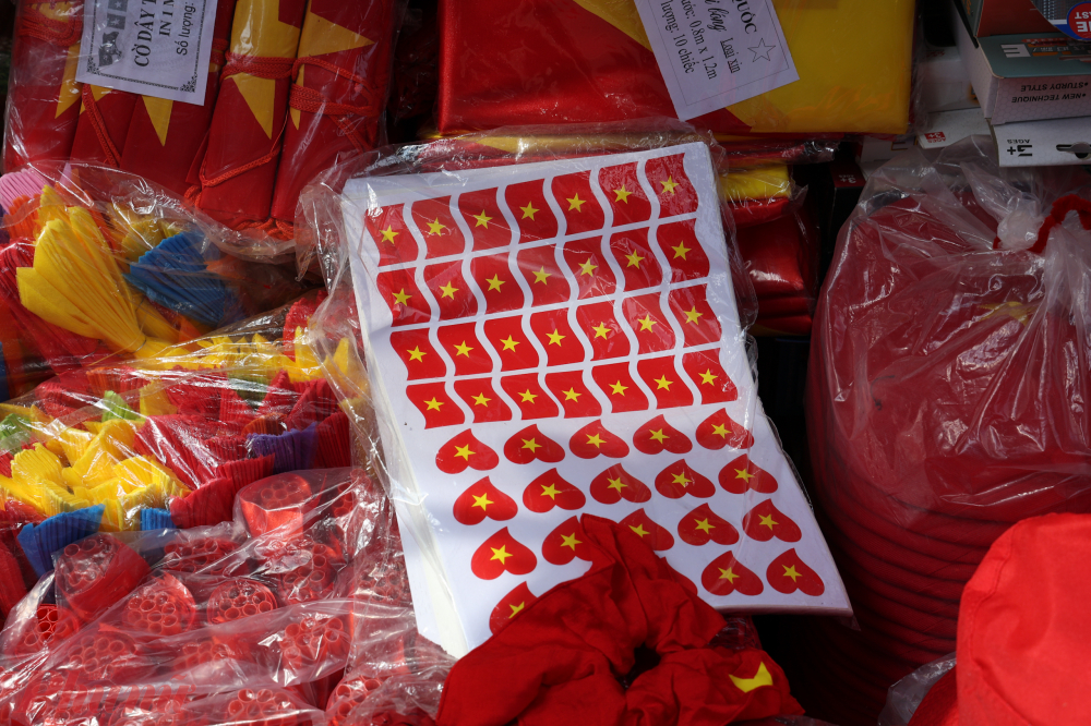 Các món đồ trang trí từ dây kim tuyến, quạt giấy, mũ chóp đỏ vàng, miếng dán sticker… xếp kín trước cửa, mời gọi người qua lại.