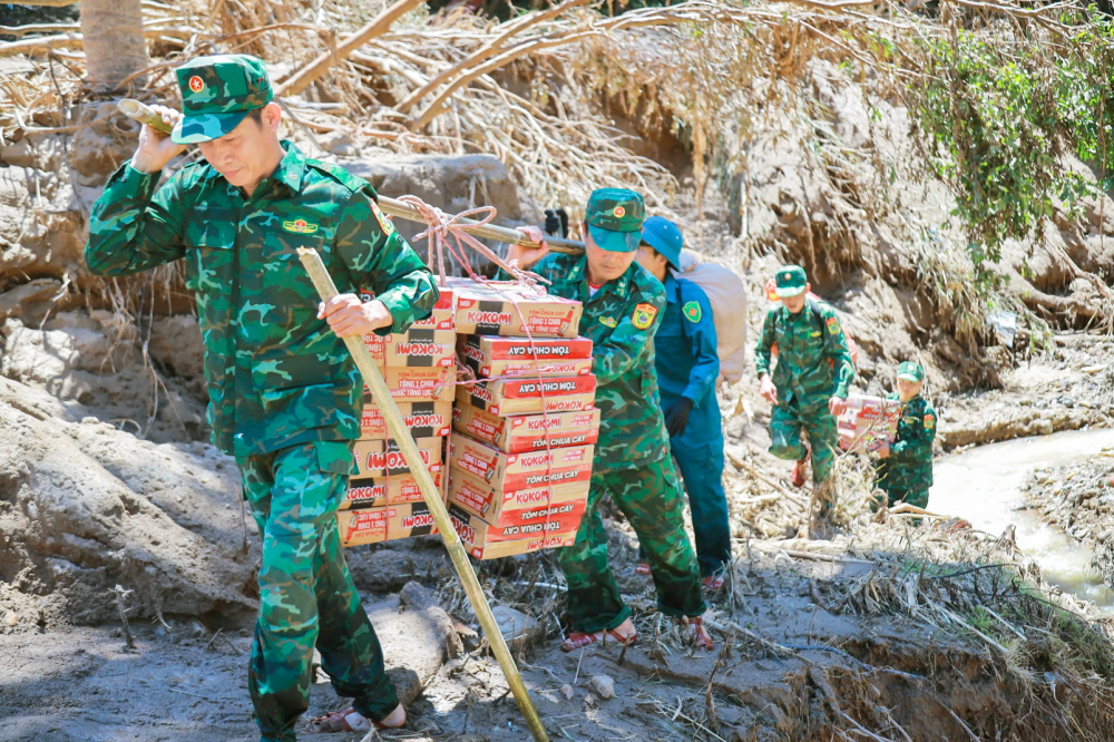 Bộ đội  biên phòng cùng cán bộ chính quyền địa phương gùi thực phẩm vào các bản bị nước lũ cô lập ở tỉnh Nghệ An - ẢNH: KHÁNH TRUNG