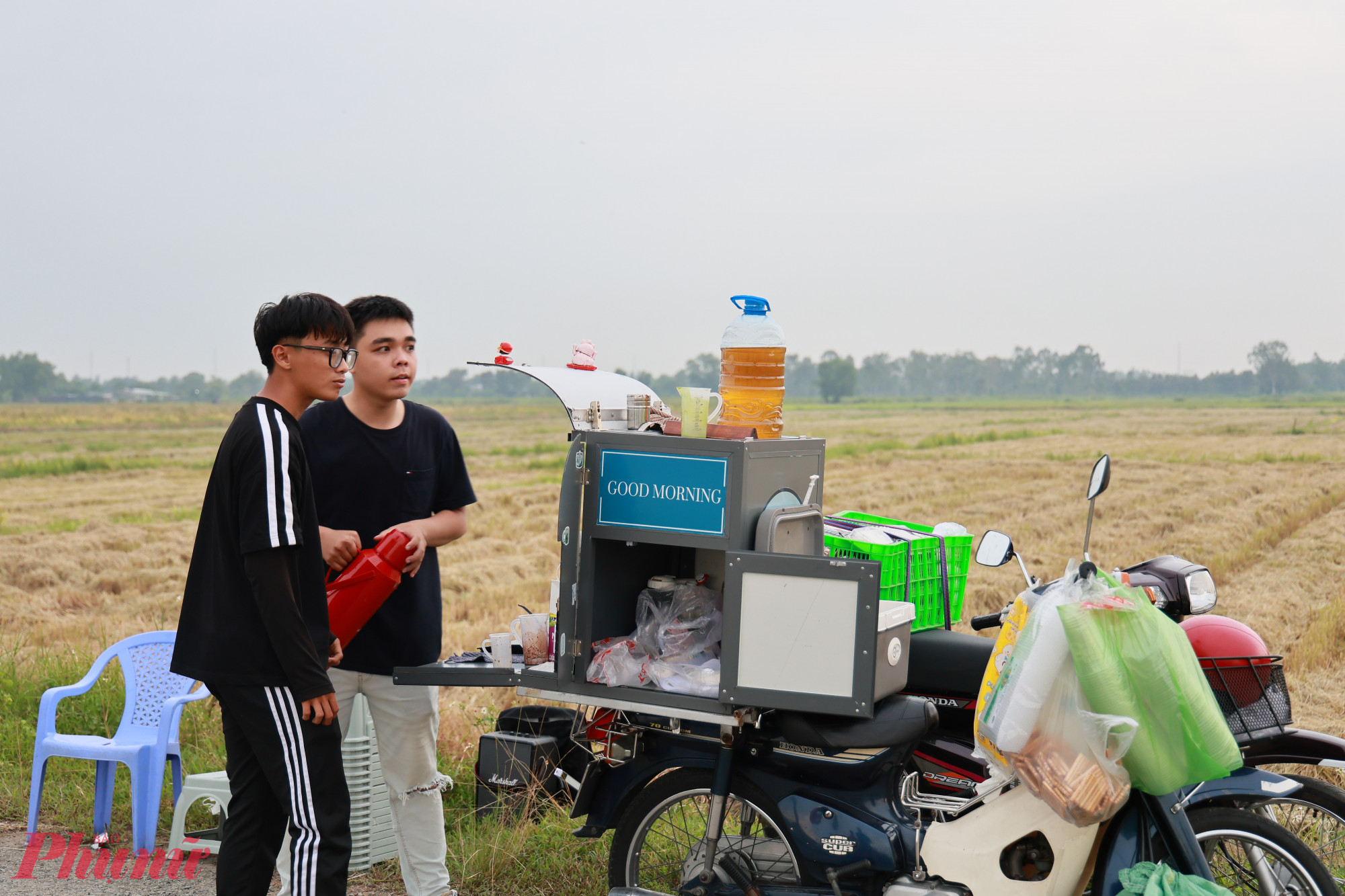 Khác với quán cà phê truyền thống với bàn ghế cố định và bảng hiệu nổi bật, quán được đặt bên lề của con đường hai bên là cánh đồng lúa đang vào vụ thu hoạch.