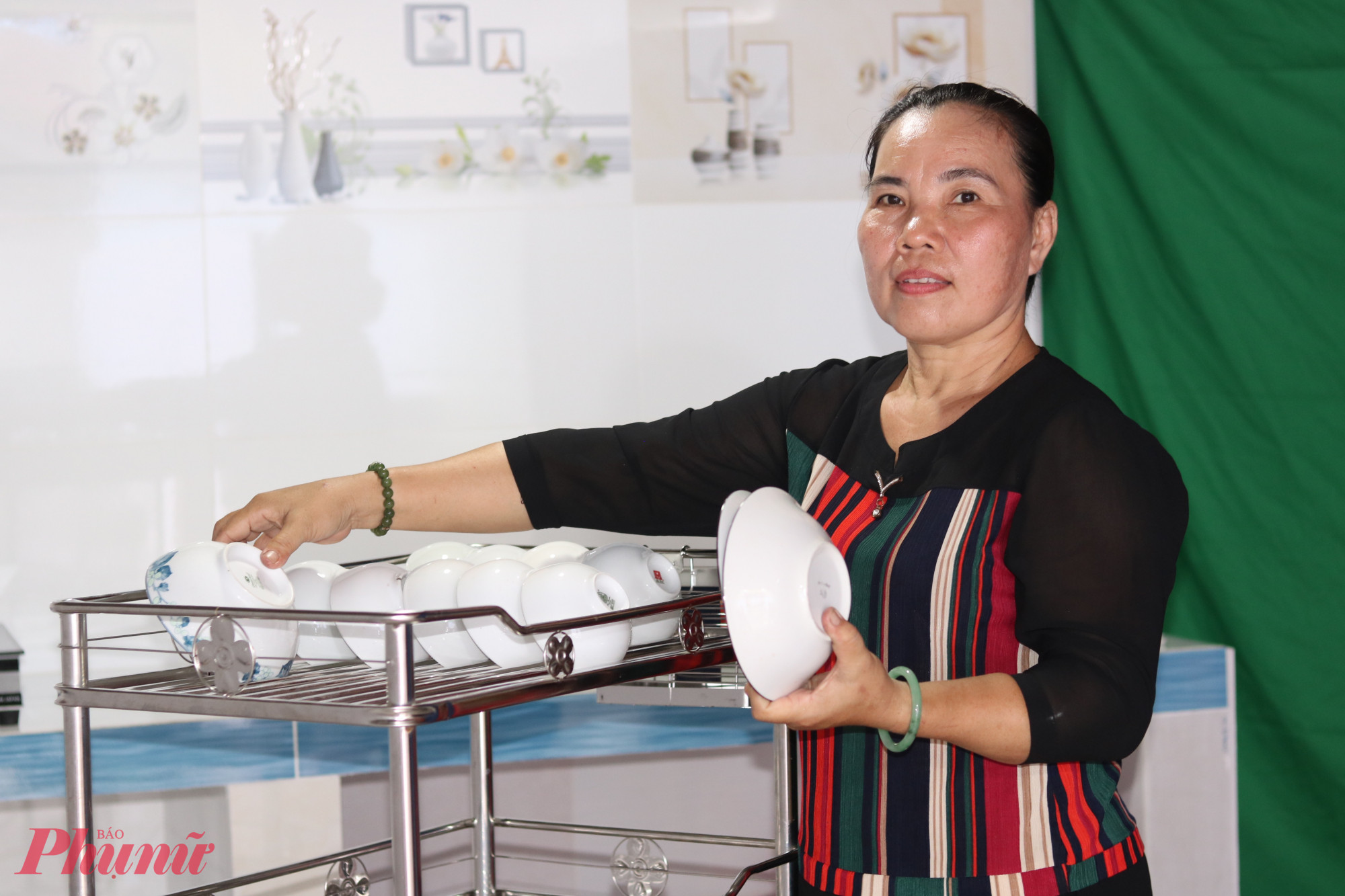 Chị Nguyễn Thị Khánh Linh phấn khởi lấy tô chén úp lên kệ inox vừa được tặng - Ảnh: Mẫn Nhi